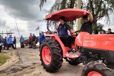 Muhammad Faiz memandu traktor untuk menarik bot selepas Majlis Penyerahan Traktor Di Bawah Program Mekanisasi Automasi 2024 Dan Penyampaian Program Industri Asas Tani pada Selasa.