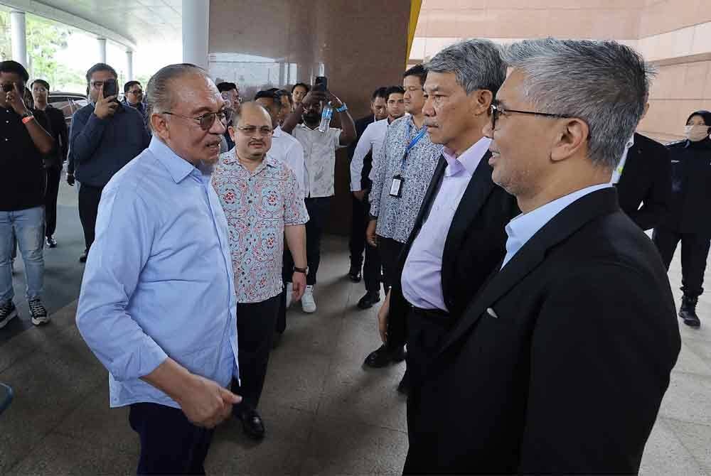 Anwar berkata sesuatu bersama Menteri Luar, Datuk Seri Mohamad Hasan dan Menteri Pelaburan, Perdagangan dan Industri, Tengku Datuk Seri Zafrul Tengku Abdul Aziz ketika tiba di tanah air pada Rabu. Foto Bernama