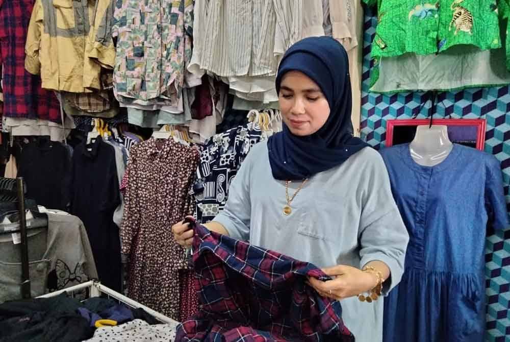 Ismawani melipat pakaian terpakai yang dijual di kedainya