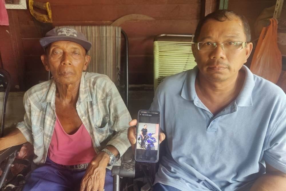 Rosli (kanan) dan bapanya, Othman Md Yazid, 78,menunjukkan gambar kenangan Allahyarham Muhammad Rosshah yang maut selepas digilis sebuah MPV apabila motosikal ditunggang terbabit dalam kemalangan tiga kenderaan di Kilometer 36 Jalan Klang-Teluk Intan di sini pada Isnin.