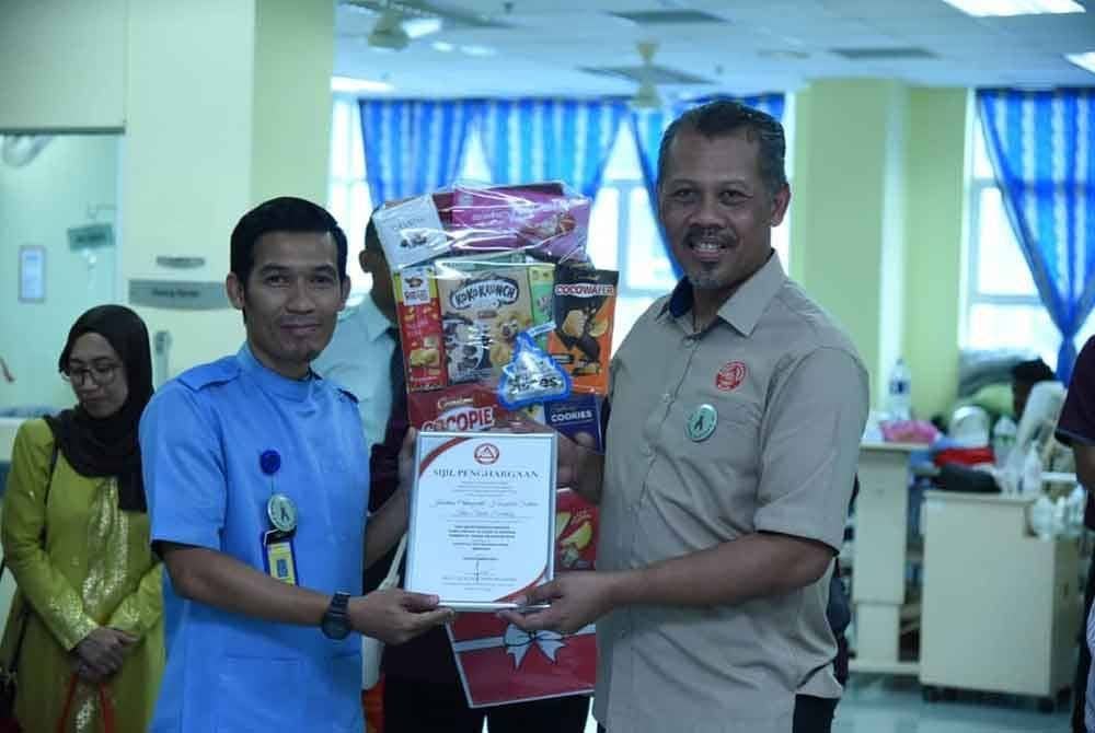 Mohd Yazid (kanan) menyerahkan sijil penghargaan dan hamper kepada wakil wad ortopedik HSIS.