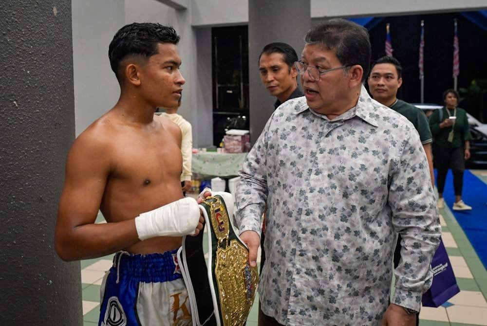 Johari (kanan) memberi dorongan kepada Mohd Haikal untuk terus bekerja keras dan berjaya dalam muay thai. Foto Bernama