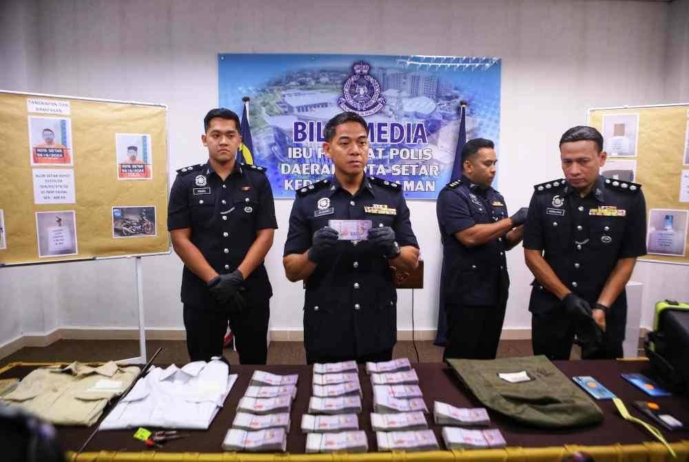 Syed Basri menunjukkan wang yang dibawa lari oleh ketiga-tiga suspek.