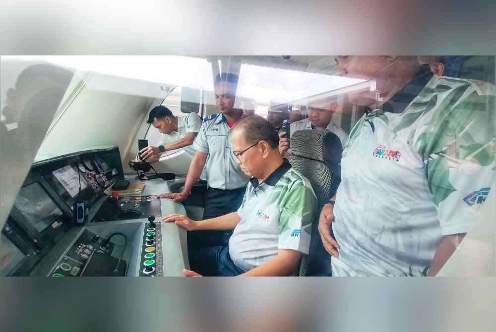 Wan Rosdy (duduk) ketika meninjau bahagian kokpit kereta api.