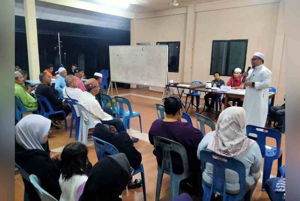 Ahmad Humaizi (berdiri) menyampaikan taklimat kepada penduduk Taman Klebang Jaya mengenai keperluan bantahan dibuat terhadap kadar baharu cukai taksiran MBI di sini pada Khamis.