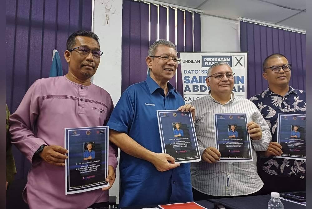 Saifuddin (dua dari kiri) menunjukkan kad laporan Ahli Parlimen Indera Mahkota di Pusat Khidmatnya pada Jumaat.