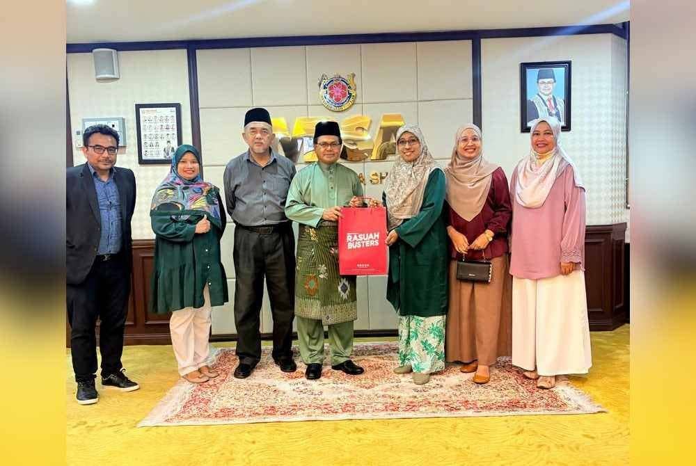 Mohd Fauzi (tengah) menerima cenderahati daripada Nurhayati yang menyertai kunjungan hormat Rasuah Busters ke MBSA pada Jumaat.