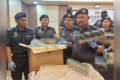 Mohd Asri (kanan) menunjukkan rokok putih yang dirampas dalam dua serbuan berasingan.