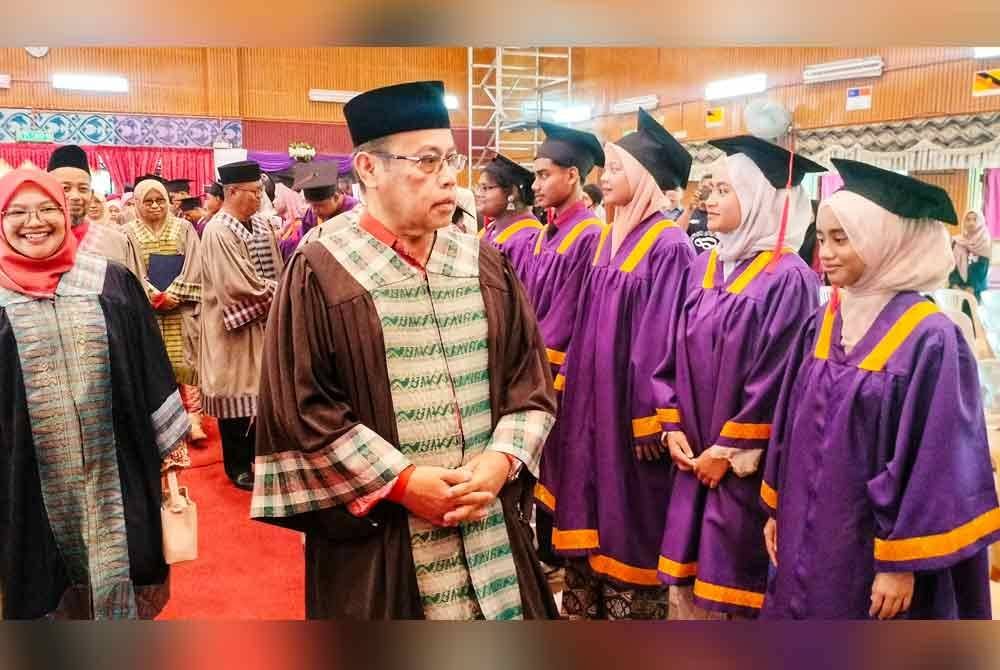 Abdul Fattah (tengah) diiringi Hamizan (kiri) menyantuni pelajar sempena majlis tersebut di SMK Padang Tengku di Lipis pada Sabtu.