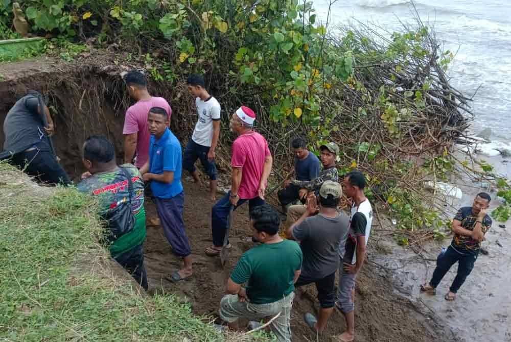 Penduduk kampung bergotong-royong mengalihkan jenazah selepas tanah perkuburan runtuh dalam kejadian hakisan di Kampung Pengkalan Maras, Kuala Nerus