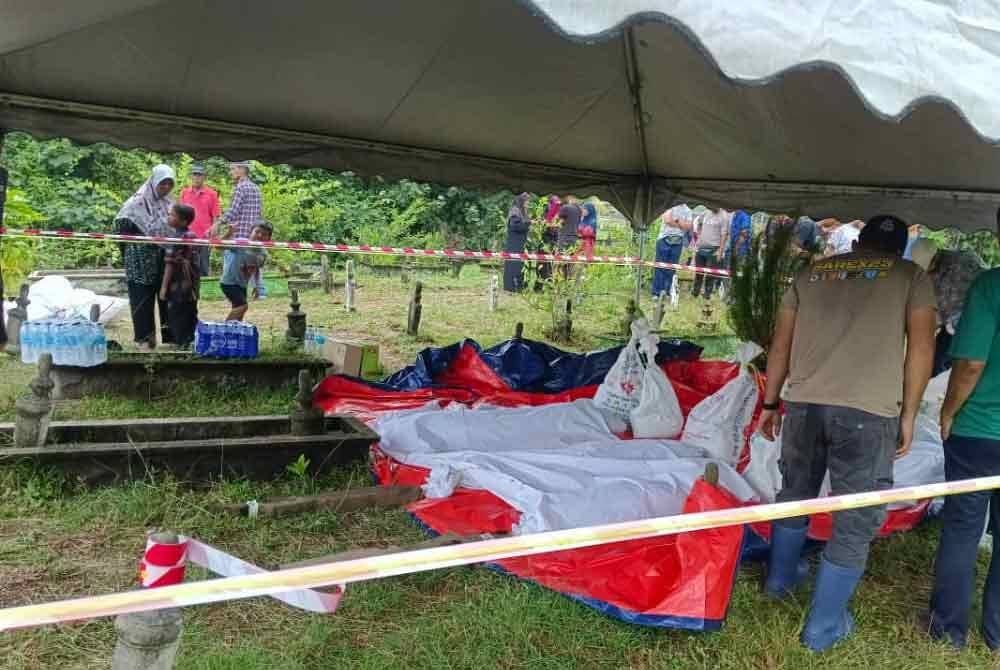Penduduk kampung bergotong-royong mengalihkan jenazah selepas tanah perkuburan runtuh dalam kejadian hakisan di Kampung Pengkalan Maras, Kuala Nerus