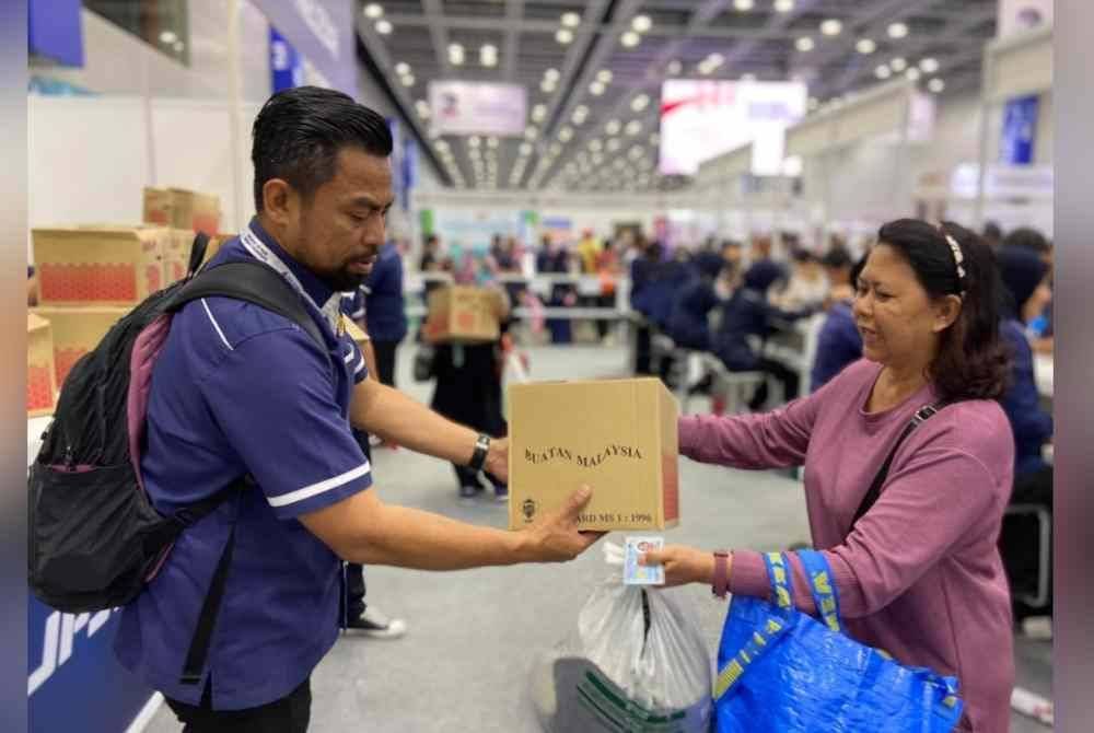 Azharul Izwan (kiri) memberi topi keledar kepada pengunjung yang hadir ke kaunter JPJ.