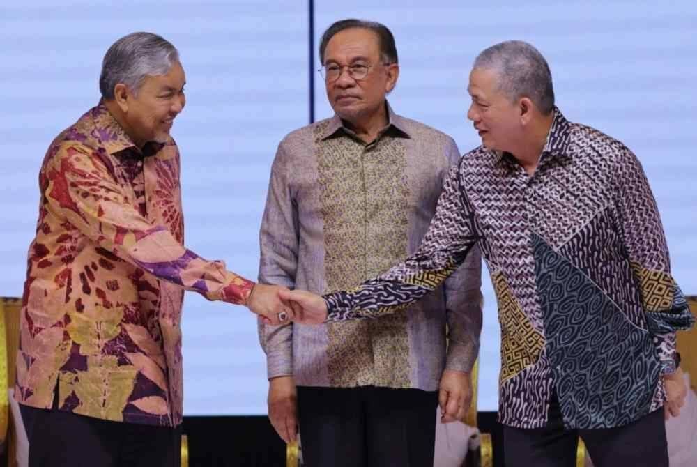 Anwar (tengah) menyaksikan 14 wakil kerajaan menurunkan tandatangan pada deklarasi Kuala Lumpur: Tekad bersama Perkhidmatan Awam Malaysia sempena program Dua Tahun Kerajaan MADANI (2TM) di Pusat Konvensyen Kuala Lumpur (KLCC) pada Sabtu. Foto Bernama