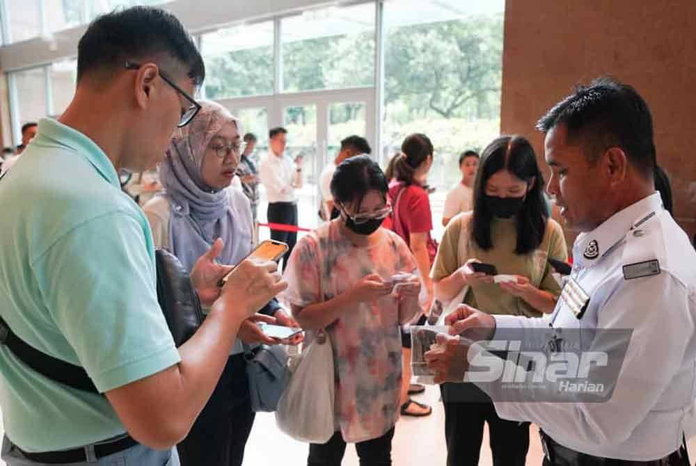 Pengunjung menyelesaikan bayaran saman trafik dengan hanya mengimbas kod QR baucar diskaun 60 peratus sambil dibantu anggota polis trafik. FOTO SINAR HARIAN-ROSLI TALIB.
