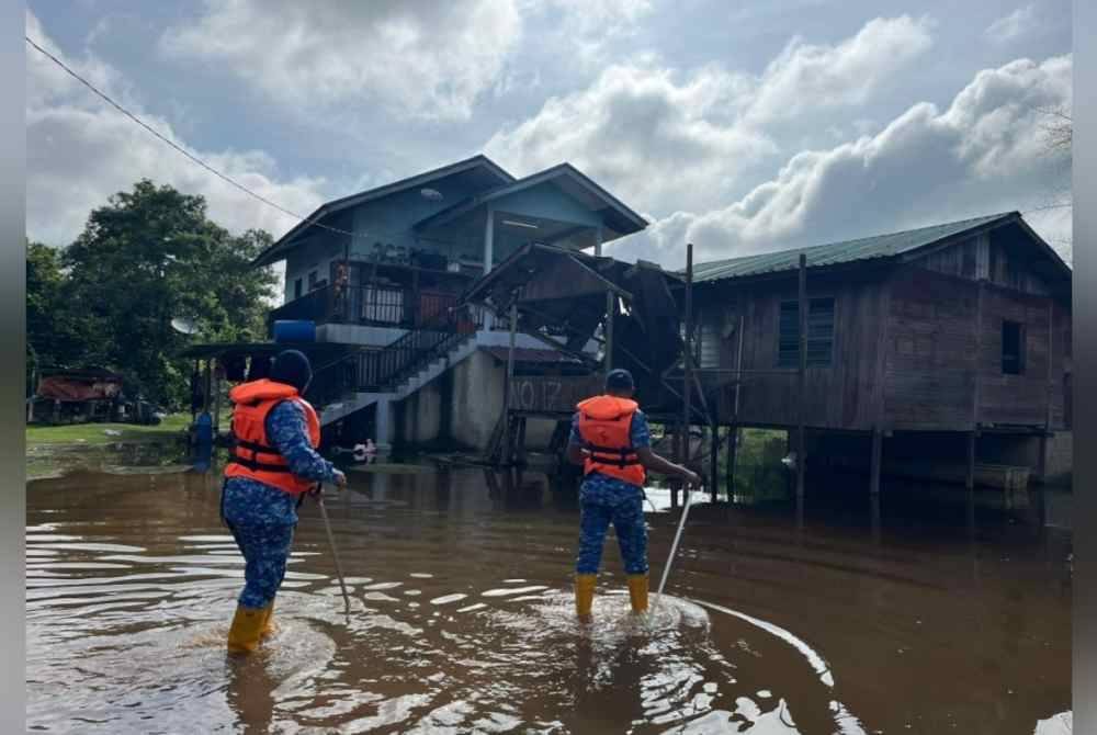 Petugas APM meninjau keadaan banjir yang melanda kawasan rumah penduduk.