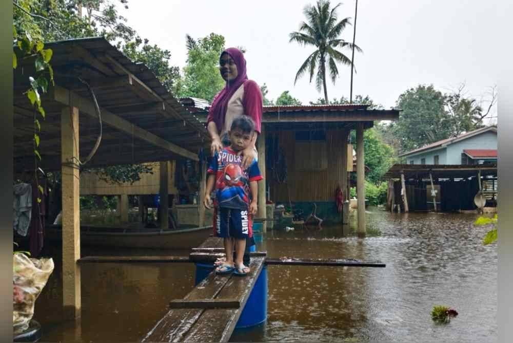 Anis Suraya bersama anak saudaranya, Muhd Adam Hakim, 4 menggunakan titi yang dibina ayahnya untuk keluar membeli barangan keperluan. Titi tersebut juga menjadi laluan untuk ibunya yang mengalami sakit lutut untuk ke klinik. Foto Bernama