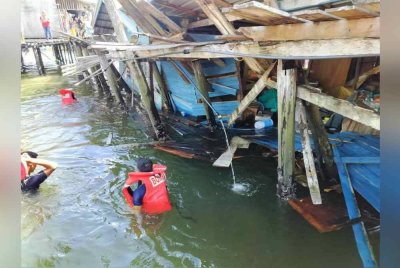 Pasukan bomba berusaha menyelamatkan penghuni yang terperangkap dalam runtuhan rumah di Kampung Air, Semporna.