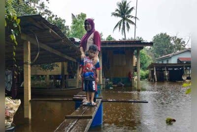Anis Suraya bersama anak saudaranya, Muhd Adam Hakim, 4 menggunakan titi yang dibina ayahnya untuk keluar membeli barangan keperluan. Titi tersebut juga menjadi laluan untuk ibunya yang mengalami sakit lutut untuk ke klinik. Foto Bernama