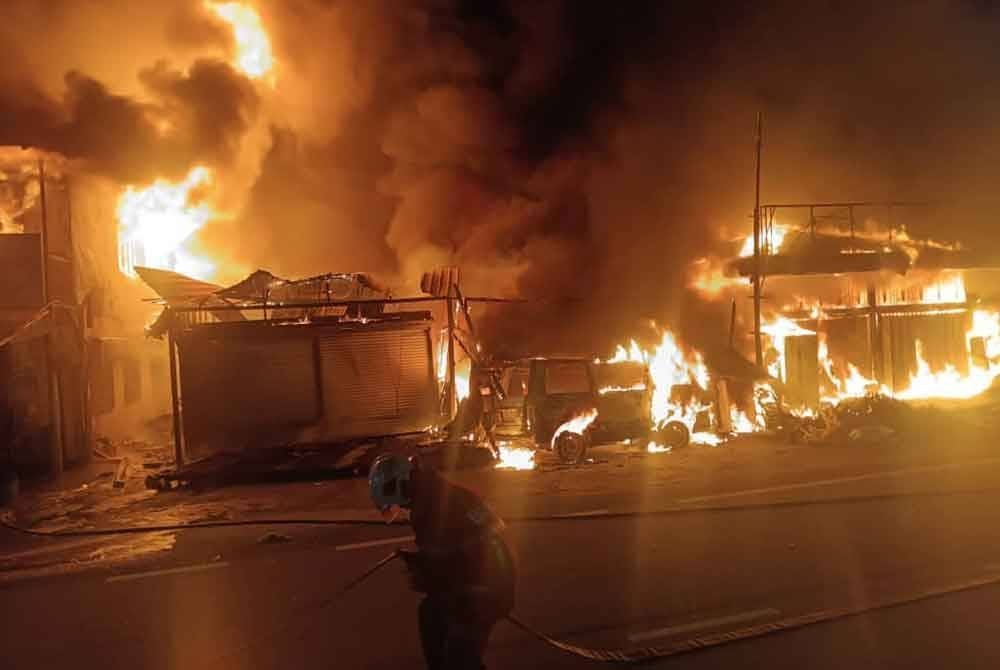 Api marak membakar rumah kedai di Kampung Sungai Chua, di sini, pada Ahad.
