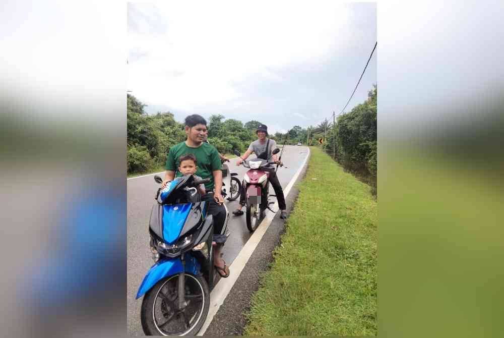 Mohd Hafizi (belakang) terpaksa berpindah selepas kawasan rumahnya dinaiki air setinggi hampir satu meter.