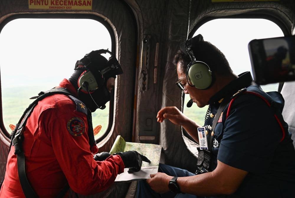 Norazam (kanan) melihat pelan semasa meninjau kawasan yang terjejas banjir yang melanda negeri ini. Foto Bernama