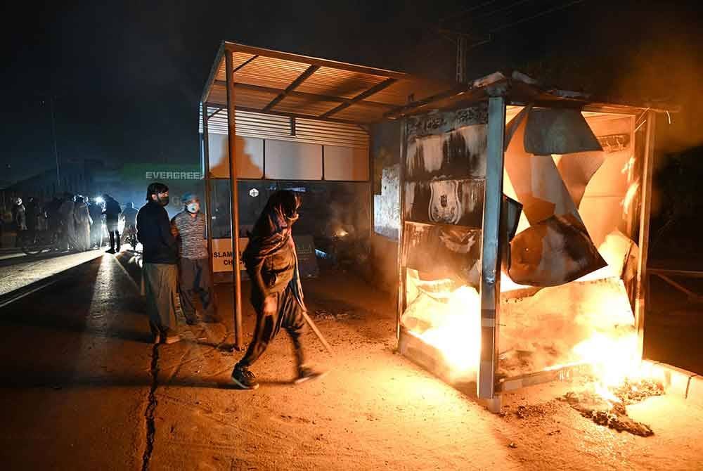 Pos pemeriksaan polis terbakar di tengah-tengah pertempuran antara penyokong Imran Khan dengan pasukan keselamatan, semasa protes menuntut pembebasan bekas Perdana Menteri itu di Islamabad. Foto Bernama