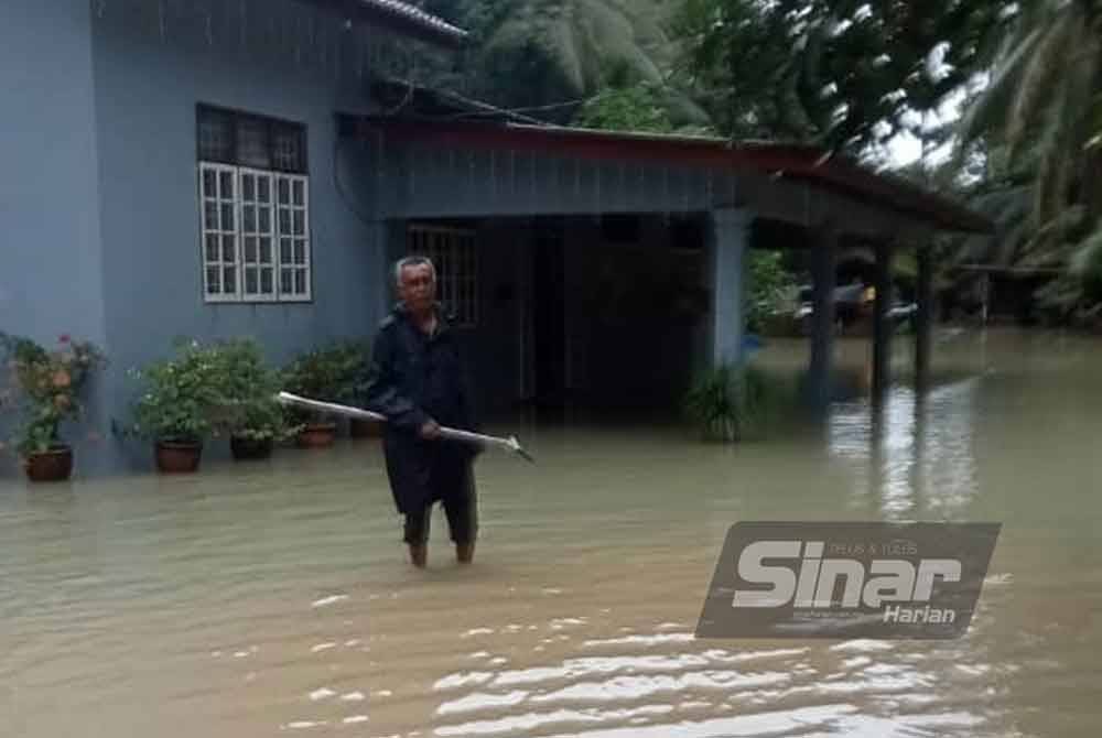 Penduduk menunjukkan keadaan air di hadapan rumahnya di Kampung Banggol Pak Esah, Pasir Puteh.