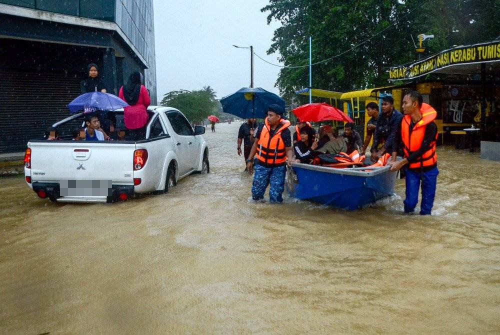 Anggota APM Kelantan memindahkan mangsa banjir yang mengalami masalah kesihatan, selepas kediamannya dinaiki air ekoran hujan lebat ketika tinjauan di Kampung Manal. Foto Bernama