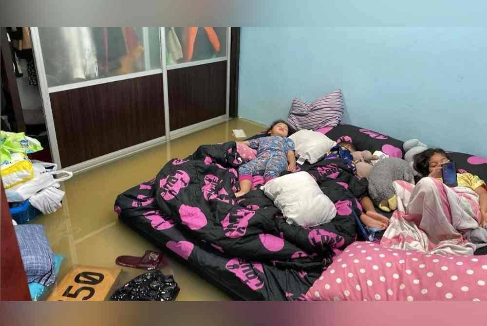 Anak-anak Siti Farah Zulaika duduk di atas katil dengan paras air semakin naik.