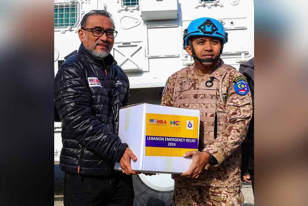 Khairil Annuar Khalid (kiri) memberi bungkusan makanan kepada salah seorang pegawai Malbatt di Beirut, Lubnan.