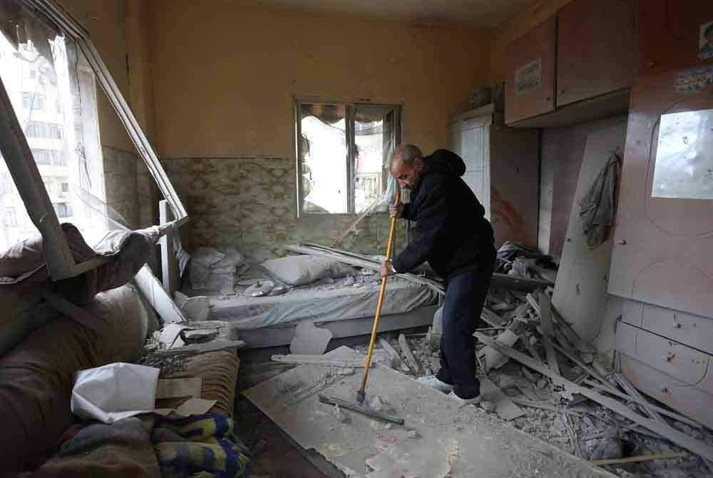 Seorang lelaki membersihkan kediamannya di pinggir selatan Beirut yang dibedil Zionis.