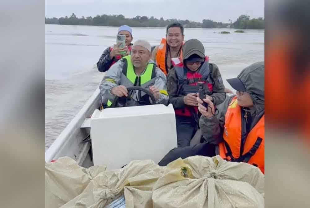 Mohd Nassuruddin (kiri) mengemudi bot membawa pek bantuan makanan kepada mangsa banjir. Foto Facebook Mohd Nassuruddin