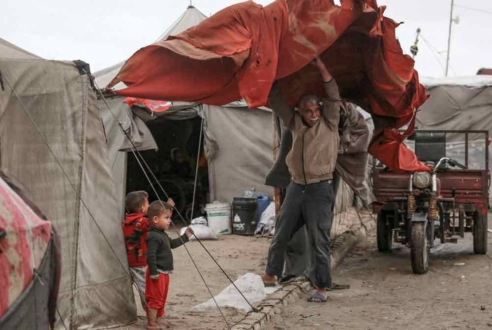 Seorang penduduk Palestin cuba menahan khemah diterbangkan angin kuat di Deir al-Balah.