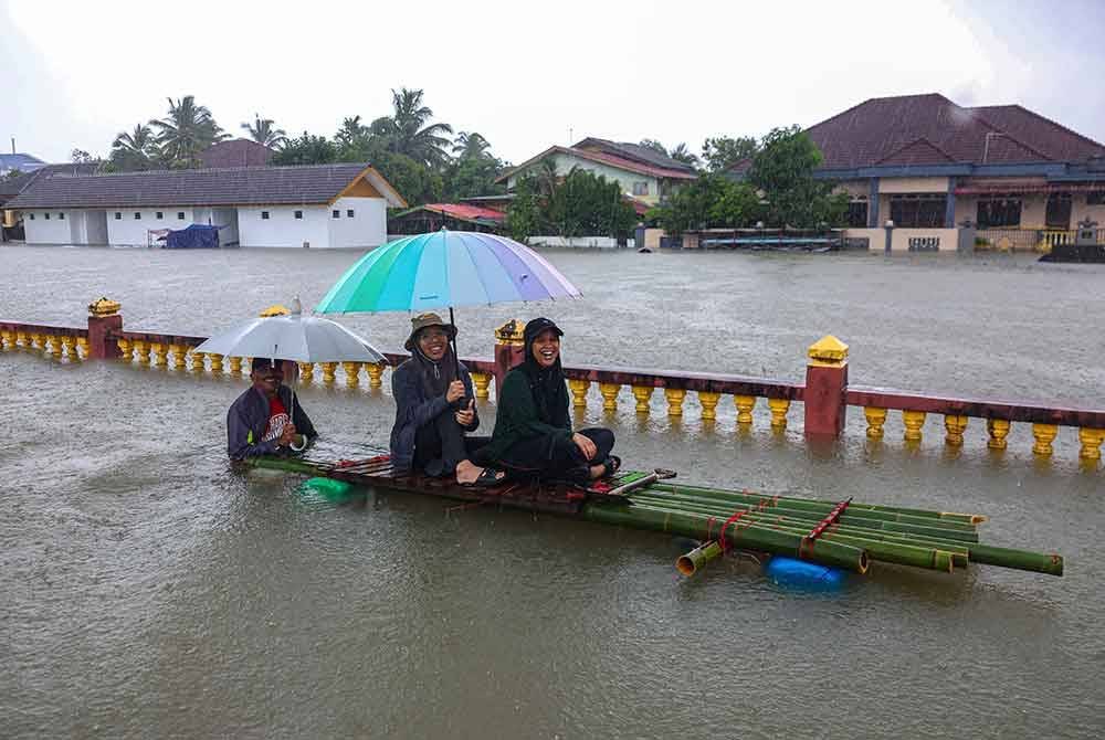 Penduduk ceria walaupun keadaan paras air banjir tinggi di sekitar tempat tinggal mereka berikutan hujan berterusan sejak beberapa hari lepas di Kampung Lati. Foto Bernama