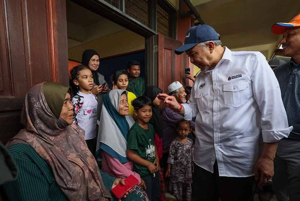 Ahmad Zahid (kanan) menyantuni mangsa banjir semasa melawat PPS Sekolah Kebangsaan Nibong, hari ini. Foto Bernama