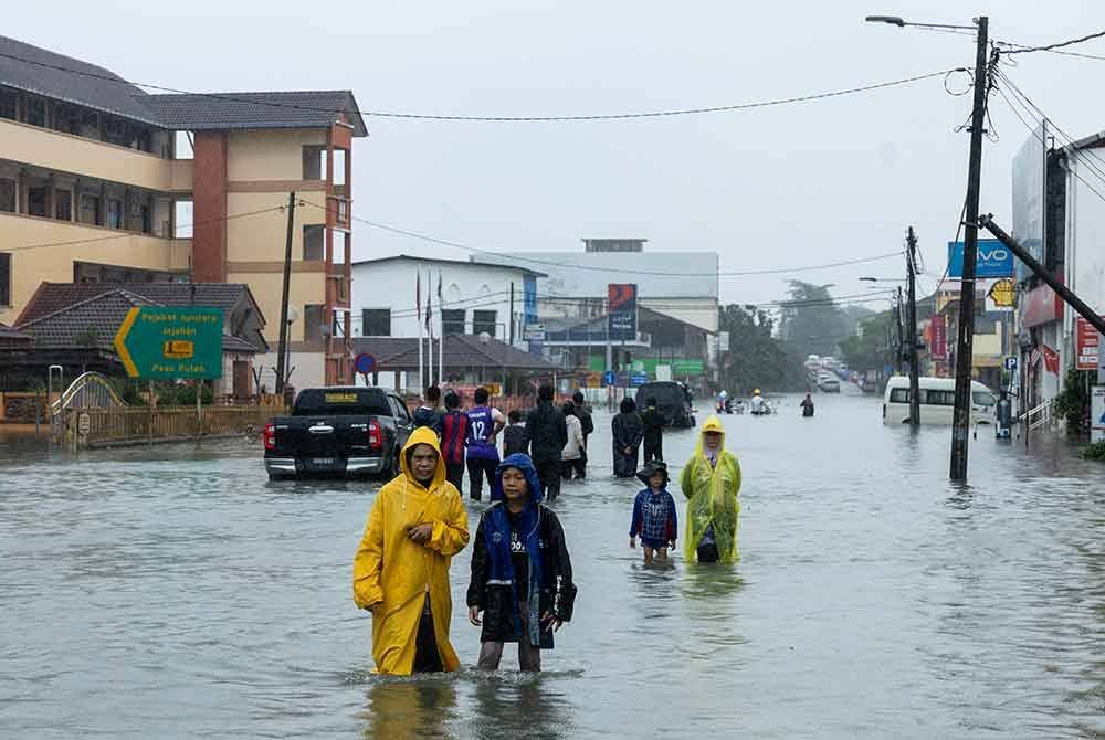 Orang ramai meredah banjir yang mula surut ketika tinjauan di Bandar Pasir Puteh hari ini. Foto Bernama