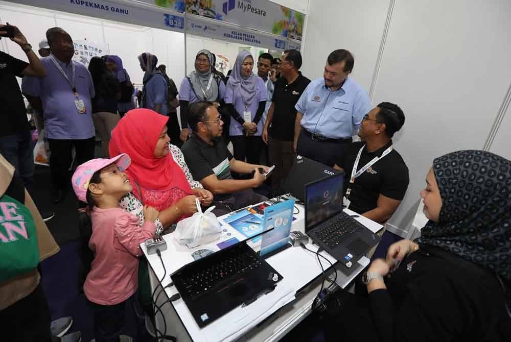Amir Hamzah (dua, kanan) bertanya khabar pengunjung Karnival My Pesara KWAP 2024 di Padang Akasia Angsana pada Ahad.