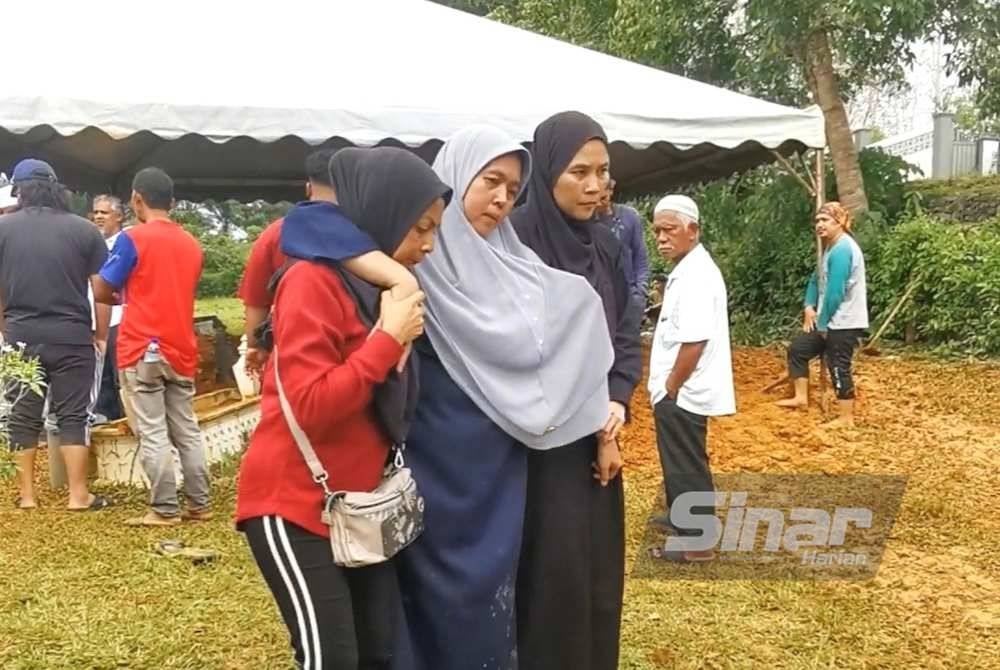 Ruziah (tengah) terpaksa dipapah kerana rebah beberapa kali selepas urusan pengebumian dua anaknya di Tanah Perkuburan Kampung Panggong, Ajil di Hulu Terengganu, pada Sabtu.