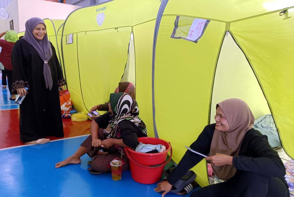 ADUN Sungai Rambai, Siti Faizah Abd Azis (kiri) bertanyakan khabar kepada mangsa banjir yang ditempatkan di pusat pemindahan sementara (PPS) di Sekolah Kebangsaan (SK) Parit Penghulu, Sungai Rambai di sini hari ini. Foto Bernama