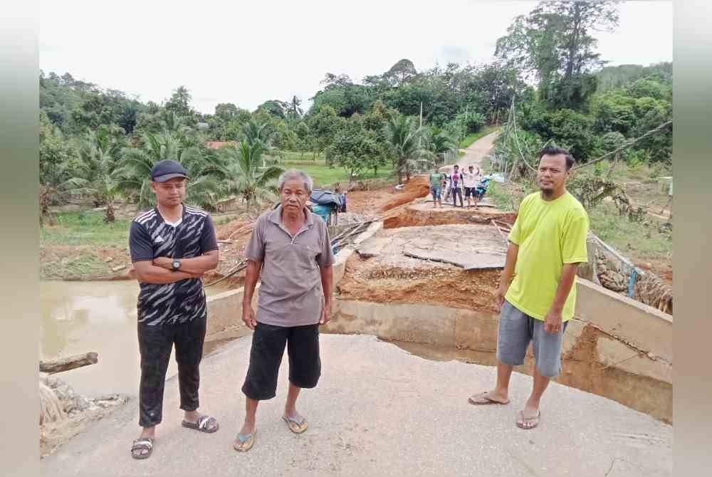 Shariff (tengah) bersama penduduk ketika meninjau keadaan jambatan berkenaan.