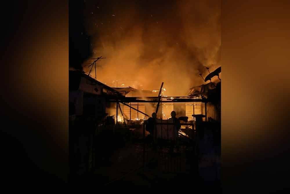 Anggota bomba bertugas sedang menjalankan kerja pemadaman melibatkan kebakaran tiga unit rumah teres di perumahan Rancangan Rumah Murah, Kuang di sini pada Sabtu.