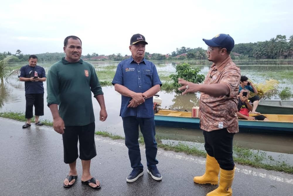 Mohamad (tengah) mendengar taklimat daripada Mohd Faizul mengenai keadaan sawah padi di Kampung Padang Kala.