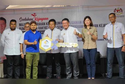 Kor Ming (tiga dari kanan) menyerahkan kunci kepada salah seorang pemilik sempena Program Sentuhan Kejayaan KPKT di Pinggiran Tanah Hitam, Chemor pada Ahad.