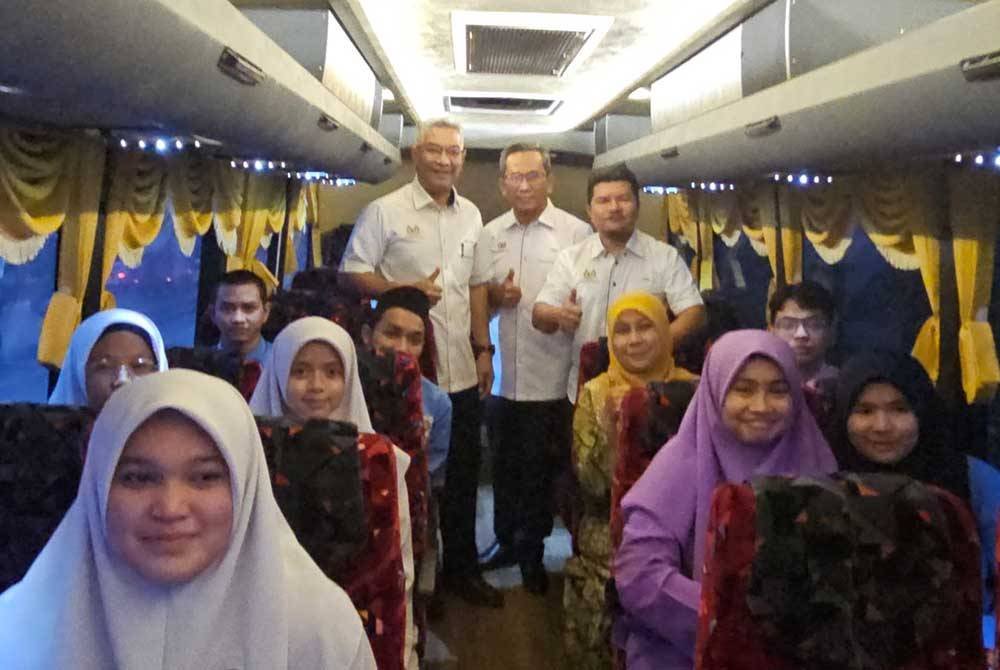 Jelani (berdiri, kiri) meninjau proses penghantaran seramai 16 calon SPM di Sekolah Menengah Kebangsaan (SMK) Kemunting di Kuala Terengganu ke pusat peperiksaan alternatif yang disediakan.