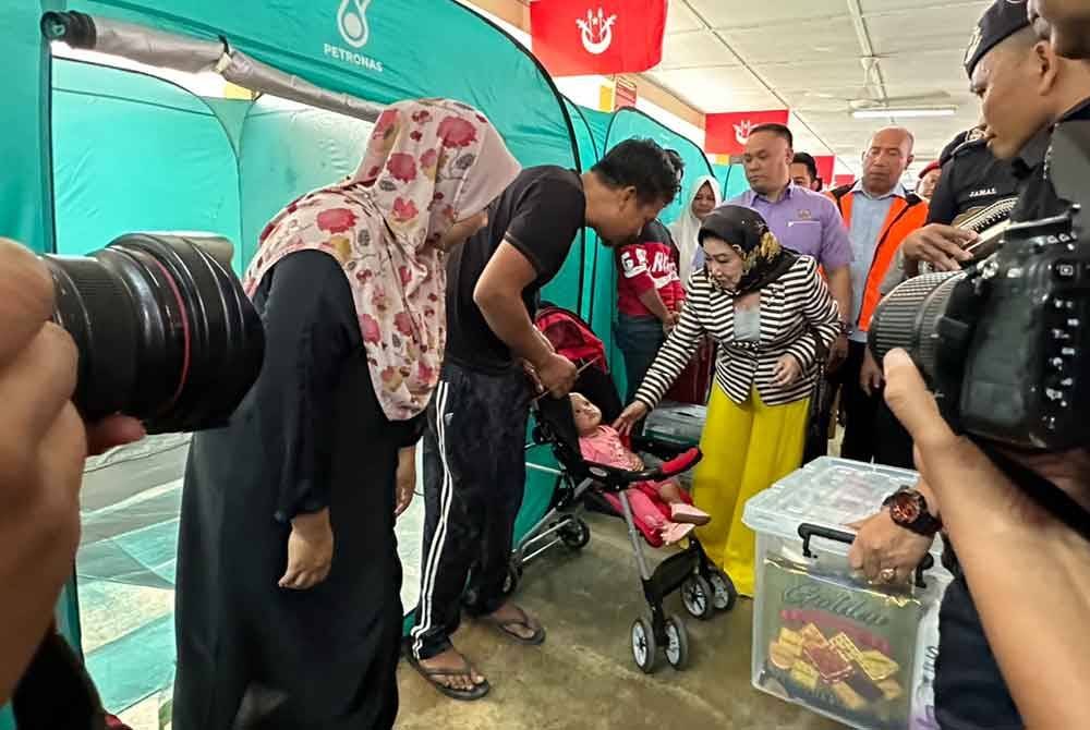 Tengku Anis (kanan) yang beramah mesra dengan mangsa banjir di PPS SK Padang Pohon Tanjung, Tumpat.