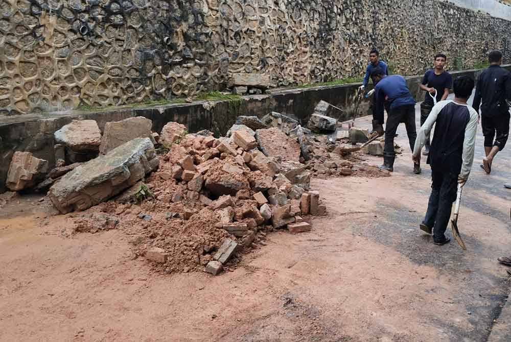 Beberapa pekerja sedang melakukan kerja-kerja pembersihan tembok runtuh di Taman Kasa Height pada Selasa.