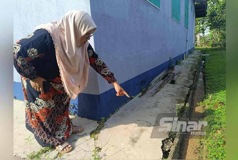 Azam menunjukkan kawasan luar rumahnya retak akibat hakisan tanah.