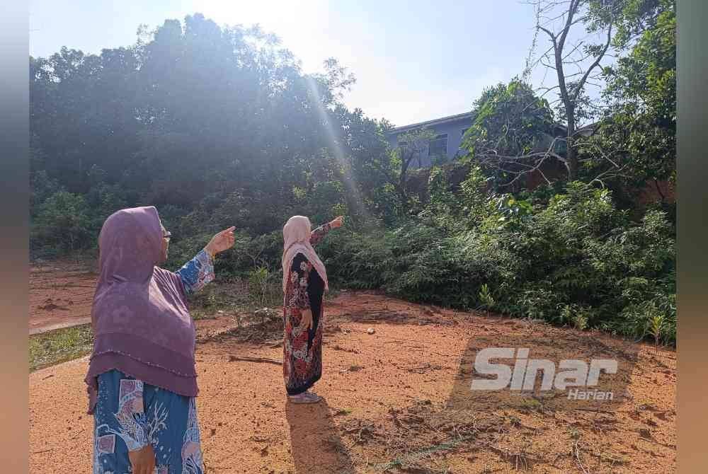 Azam (kanan) dan Nik Jamaliah menunjukkan keadaan rumah yang diancam hakisan tanah.