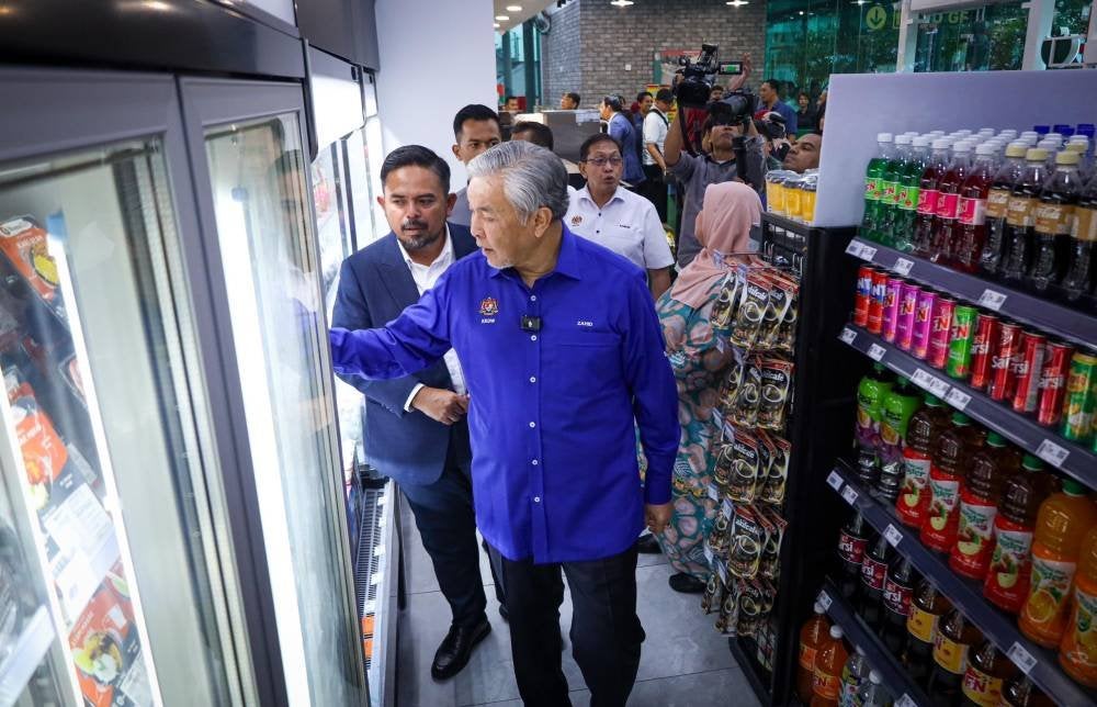 Manndzri (kiri) memberi penerangan ringkas mengenai RisSMart24 kepada Ahmad Zahid ketika sesi lawatan.