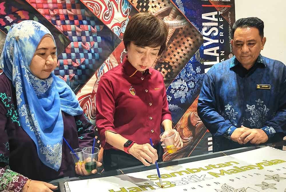 Nicole (tengah) cuba mencanting batik di ruang pameran sempena sambutan Hari Batik Malaysia 2024.